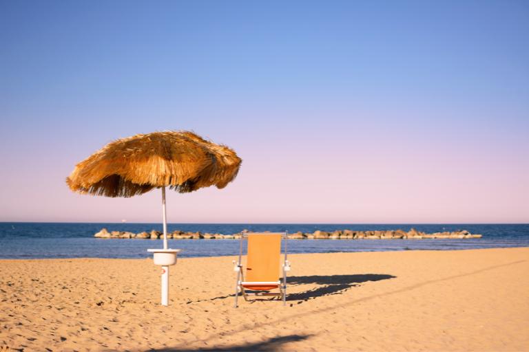 a chair and an umbrella on a sandy beach in abruzzo