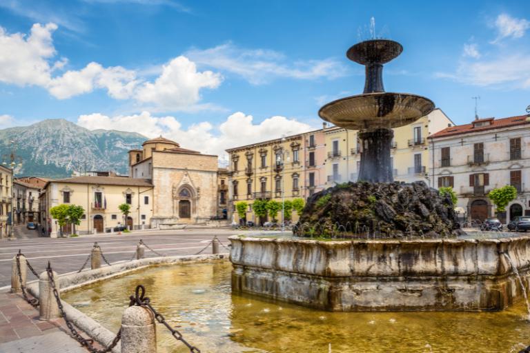 Sulmona view of a fountain with a church and mountains in the background