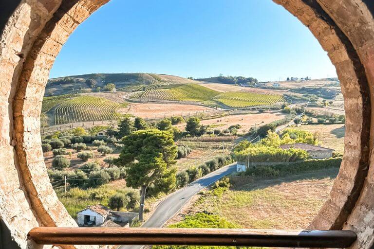 Abruzzo countryside framed by a round brick window at Torre del Cerrano | Abruzzo itinerary 
